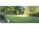 An expansive green backyard is surrounded by mature trees, flowering bushes and lush landscaping at 210 Shillings Chase Dr, Cary, NC 27518