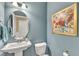 Powder room features a pedestal sink, toilet, oval mirror, floral art, and blue walls at 2305 Everstone Rd, Wake Forest, NC 27587