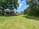 Spacious backyard featuring lush green grass and mature trees, and a covered patio at 235 Stephenson Rd, Benson, NC 27504