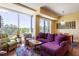 Bright living room with a purple sofa, wooden floors, and golf course views from the large window at 2410 Environ Way, Chapel Hill, NC 27517