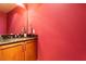 This powder room features granite counters, wood cabinets and vibrant red walls at 2410 Environ Way, Chapel Hill, NC 27517