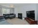 Relaxing living room featuring a fireplace, large TV, ceiling fan, and plush seating for comfort and entertainment at 2412 Chartwell Ln, Graham, NC 27253