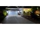 Well-lit exterior view of a stone home with a two-car garage, highlighting its charming curb appeal at night at 2421 Beckwith Rd, Apex, NC 27523