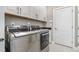 Modern laundry room featuring white cabinetry, sleek stainless-steel appliances, and tiled flooring at 2421 Beckwith Rd, Apex, NC 27523