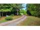 Gravel driveway winding through a canopy of trees leads to a private and serene property at 260 Woody Ln, Oxford, NC 27565