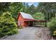 A red building features an attached covered parking area and verdant landscaping at 260 Woody Ln, Oxford, NC 27565