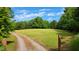 Picturesque driveway leads to a vast, verdant lawn, framed by mature trees, creating a park-like setting at 260 Woody Ln, Oxford, NC 27565