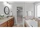 Bathroom with granite-topped vanity, large soaking tub, and doorway to carpeted bedroom at 2712 Peachleaf St, Raleigh, NC 27614