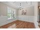 Classic dining room featuring hardwood floors, wainscoting, a chandelier, and a large window offering natural light at 2712 Peachleaf St, Raleigh, NC 27614