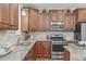 Well-lit kitchen featuring granite countertops, stainless steel appliances, and custom wood cabinetry at 2712 Peachleaf St, Raleigh, NC 27614