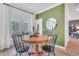 Dining room with a round wooden table, black chairs, green accent wall and view to outdoor living at 287 Alice Trace Place, Angier, NC 27501