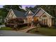 Inviting brick home with manicured lawn, landscape lighting and arched windows at sunset at 308 Thomas Dr, Clayton, NC 27520