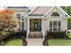 A house with a brick facade featuring a charming front porch with landscaped garden and walkway at 308 Thomas Dr, Clayton, NC 27520