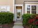 Welcoming entrance featuring a glass front door framed by verdant bushes and vibrant red roses at 3711 Ramblewood, Durham, NC 27713
