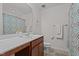 Bright bathroom featuring wood cabinets, stylish countertop, a framed mirror, and a patterned shower curtain at 3936 White Kestreg Dr Dr, Raleigh, NC 27616