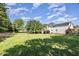 Expansive backyard with lush green grass, mature trees, and a view of the home's exterior at 4117 Stansted Dr, Fuquay Varina, NC 27526