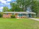 Charming single-story brick home featuring a well-maintained lawn, cozy carport, and inviting front porch at 413 Winterlochen Rd, Raleigh, NC 27603