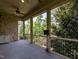 A covered porch with stone accents offers outdoor seating and a view of lush trees and landscaping at 4143 Gardenlake Dr, Raleigh, NC 27612