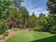 Backyard with lush greenery, including a small pond area, and well-maintained lawn, enclosed by an iron fence at 4143 Gardenlake Dr, Raleigh, NC 27612