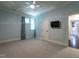 This bedroom features carpeted floors, a ceiling fan, large windows, and a door to the hallway at 4143 Gardenlake Dr, Raleigh, NC 27612