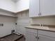This laundry room has tiled floors, a utility sink, plenty of cabinets, and washer and dryer hookups at 4143 Gardenlake Dr, Raleigh, NC 27612