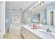 Bathroom featuring a double vanity with marble countertop, soaking tub, and natural light from the window at 4420 Dula St, Durham, NC 27705