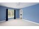 Blue bedroom with neutral carpet, ceiling fan, and natural light from window at 4913 Stockton Way, Durham, NC 27707