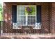 Inviting front porch with seating, flowers and black railing in front of brick wall at 4913 Stockton Way, Durham, NC 27707