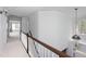 Well-lit hallway with white carpet, wooden handrail, and chandelier at 4913 Stockton Way, Durham, NC 27707
