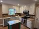 Bright kitchen features stainless steel appliances, white cabinets and center island with stone countertops at 501 Samara St, Apex, NC 27502