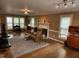 Cozy living room featuring leather couch, fireplace with intricate paneling, and light from large windows at 501 Samara St, Apex, NC 27502