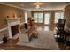 Cozy living room featuring leather couch, fireplace with intricate paneling, and light from large windows at 501 Samara St, Apex, NC 27502