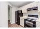 A well-lit kitchen featuring modern black appliances, white cabinets, and wood-look floors at 600 Audubon Lake Dr # 6B13, Durham, NC 27713