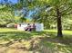 Charming single-story home with a red porch and metal carport on a large lot with mature trees at 6579 Sidney Cottrell Rd, Oxford, NC 27565