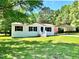Charming single-story home with a metal carport, lush green lawn, and mature trees at 6579 Sidney Cottrell Rd, Oxford, NC 27565