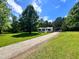Exterior view showcasing the home's driveway, metal carport, and surrounding greenery at 6579 Sidney Cottrell Rd, Oxford, NC 27565
