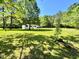 Expansive front yard view of home featuring a metal carport and lush surrounding trees at 6579 Sidney Cottrell Rd, Oxford, NC 27565