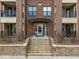 Close-up of building entryway with stairs, stone wall, glass door, and brick facade at 700 Finsbury St # 105, Durham, NC 27703