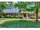 Charming brick home featuring a lush green lawn, mature trees, and classic shutters at 7204 Bellweather N Ct, Raleigh, NC 27615