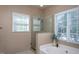 The primary bathroom has a glass-enclosed shower and soaking tub beneath two bright windows at 802 Wakehurst Dr, Cary, NC 27519