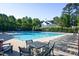 Community pool featuring lounge chairs and tables, surrounded by lush green trees, perfect for relaxation and recreation at 802 Wakehurst Dr, Cary, NC 27519