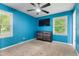 Vibrant bedroom with blue walls, a ceiling fan, and a dresser, with large windows and neutral carpet at 901 Currin Perry Rd, Zebulon, NC 27597