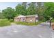 Charming brick ranch-style home with a covered front porch and spacious driveway nestled among mature trees at 901 Currin Perry Rd, Zebulon, NC 27597