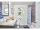 Bathroom featuring a shower, dark wood cabinets and a single window for natural light at 909 Goodwin Rd, Durham, NC 27712
