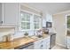 Bright kitchen featuring butcher block countertops, white cabinets, and a stainless steel dishwasher at 909 Goodwin Rd, Durham, NC 27712