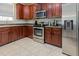 This kitchen features wood cabinets, stainless steel appliances and light-colored tile flooring at 100 Full Moon Ct, Garner, NC 27529
