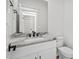Well-lit half-bath with granite countertop and stylish black fixtures, complementing the white cabinets at 1009 Rhino Bnd, Oxford, NC 27565