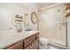 Bathroom with a glass-door shower, wood vanity, decorative shelves and a round mirror at 1009 Travern Dr, Raleigh, NC 27603