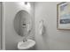 Clean powder room featuring a pedestal sink, a round mirror, and modern decor at 1011 Canary Pepper Dr, Durham, NC 27713