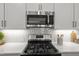 Close-up of a kitchen featuring stainless steel microwave, range, white countertops, and light gray cabinets at 1011 Canary Pepper Dr, Durham, NC 27713